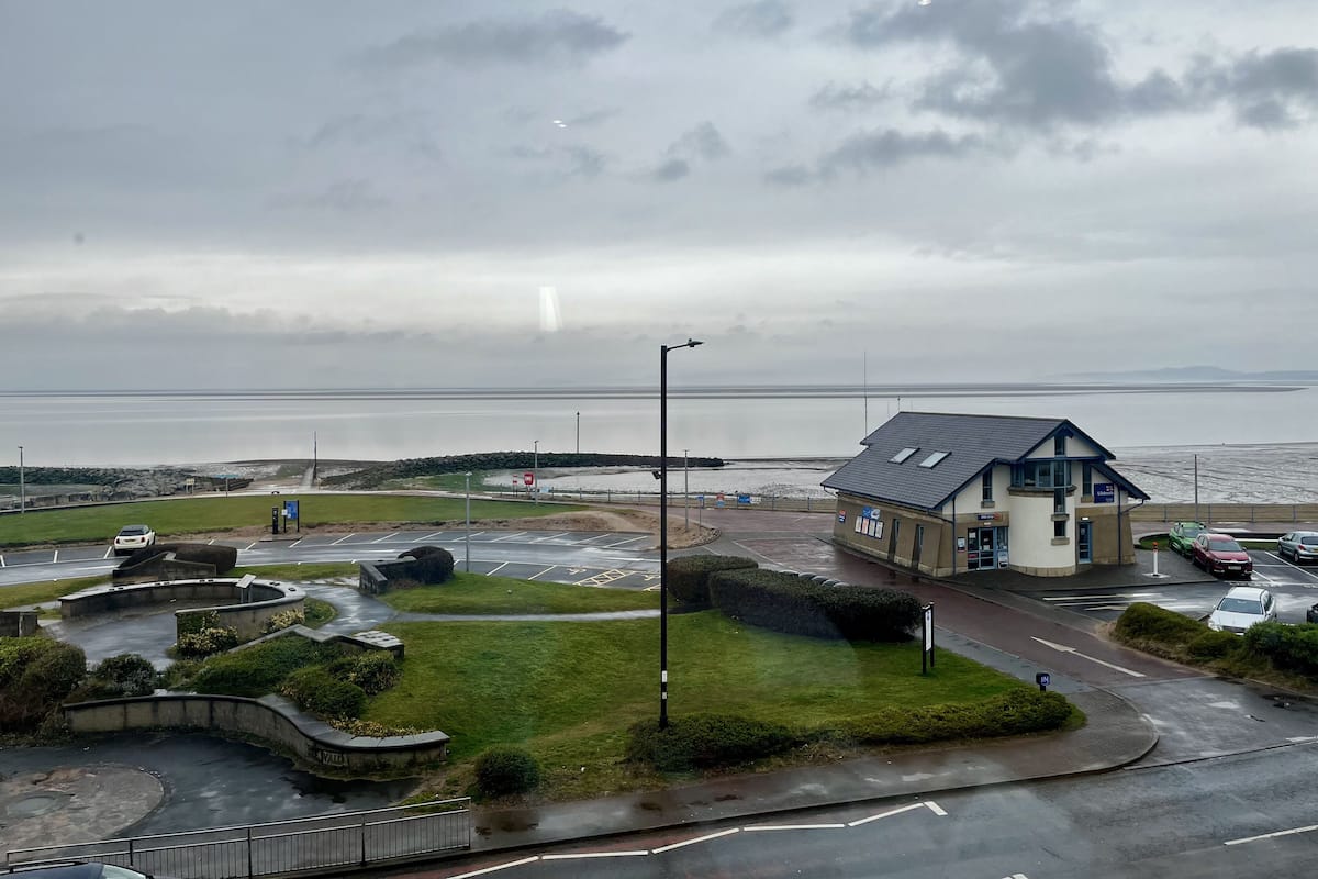 A coastal building with a parking area and a view of the sea.