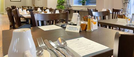 A dining area with tables set for service, including utensils and a menu.