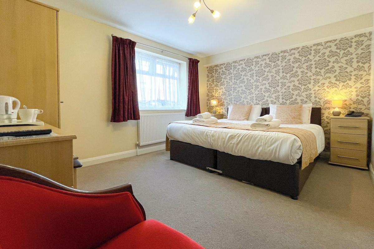 A bedroom with a bed, bedside tables, a wardrobe, and a red chair.