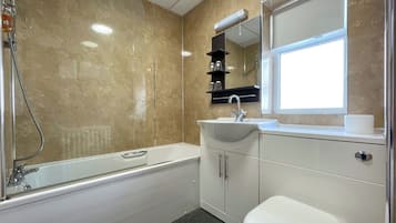 A modern bathroom with a bathtub, sink, and toilet.