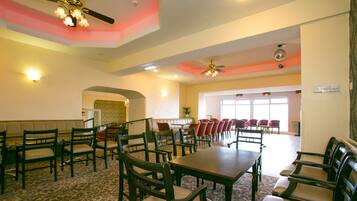 A spacious dining area with high ceilings, ceiling fans, and a patterned carpet.