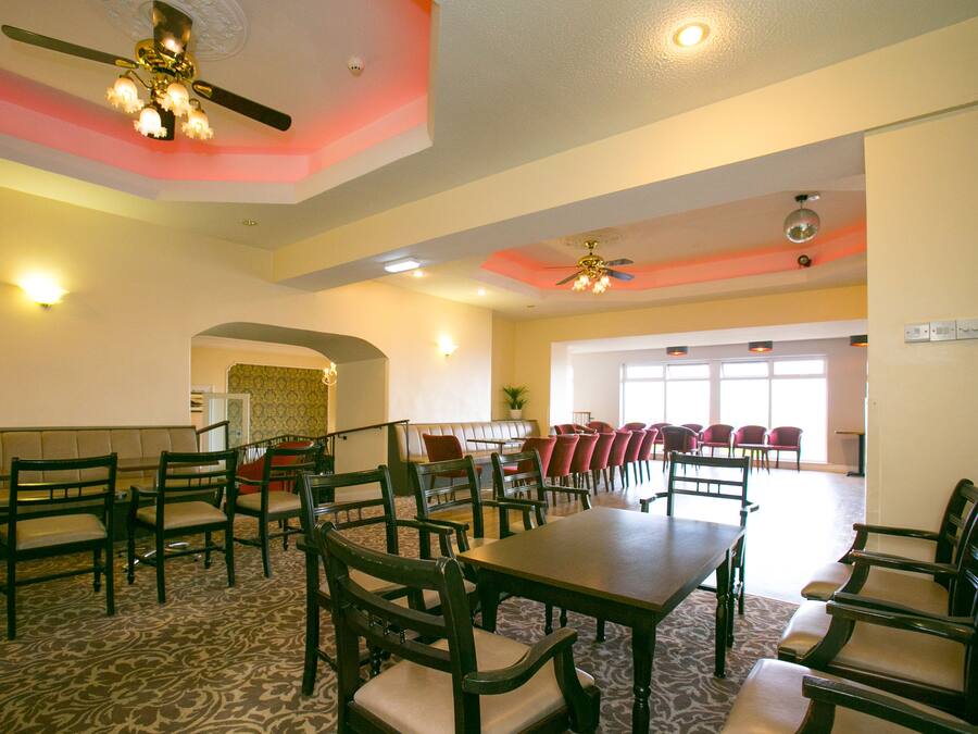 A spacious dining area with high ceilings, ceiling fans, and a patterned carpet.