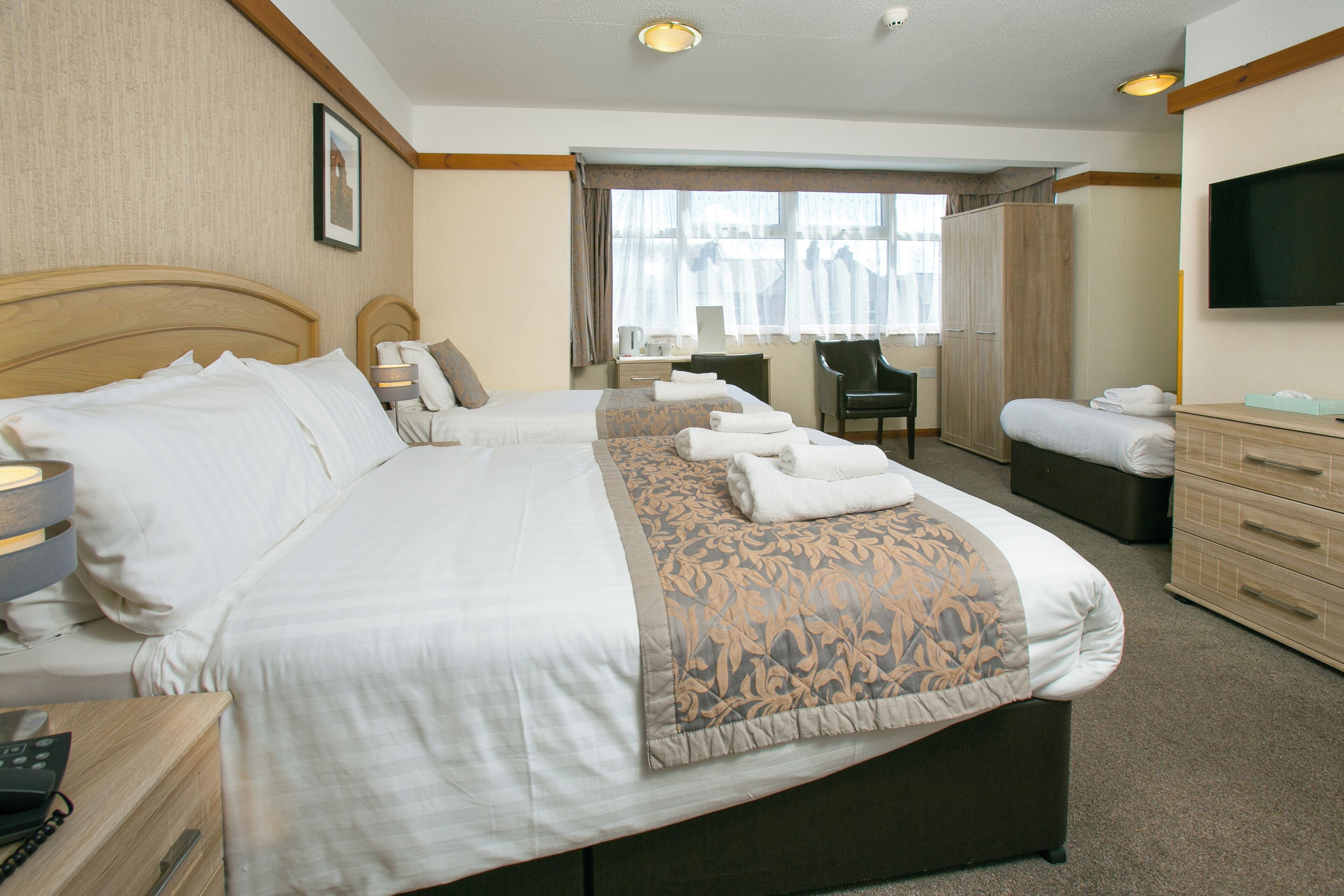 Een hotelkamer met een groot bed, een bureau, een stoel, een televisie en een kledingkast.