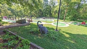 A park with a miniature golf course, a statue, and a red sculpture.