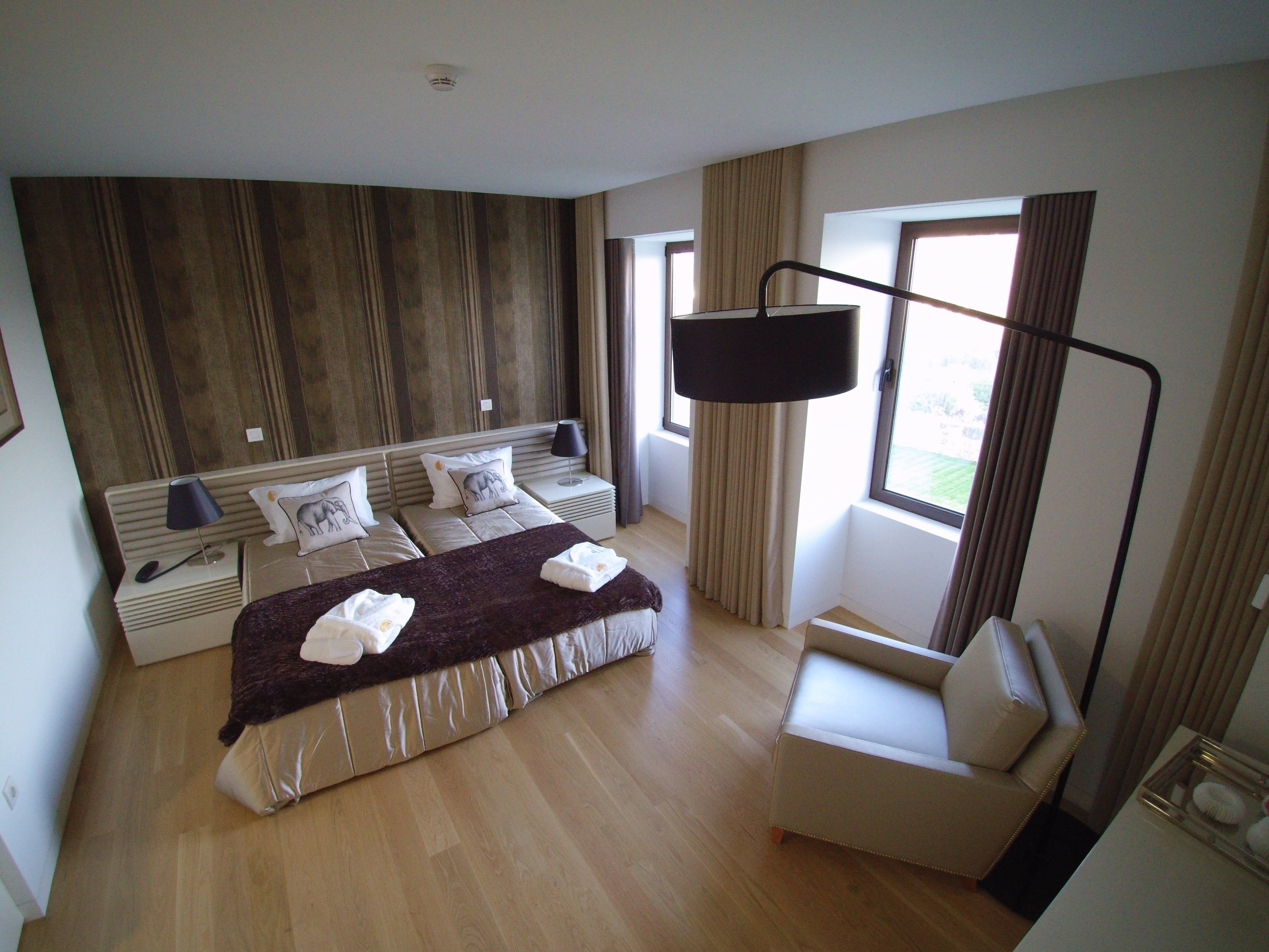 A hotel room with a large bed, two bedside tables, a chair, and a window with curtains.
