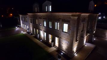 Un edificio de piedra con múltiples ventanas y un exterior iluminado durante la noche.
