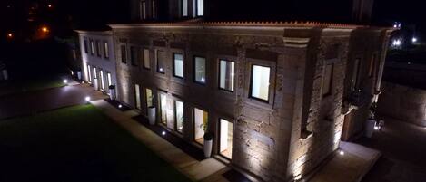 A stone building with multiple windows and a well-lit exterior at night.