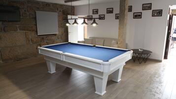A pool table in a room with stone walls, a whiteboard, and framed pictures on the wall.