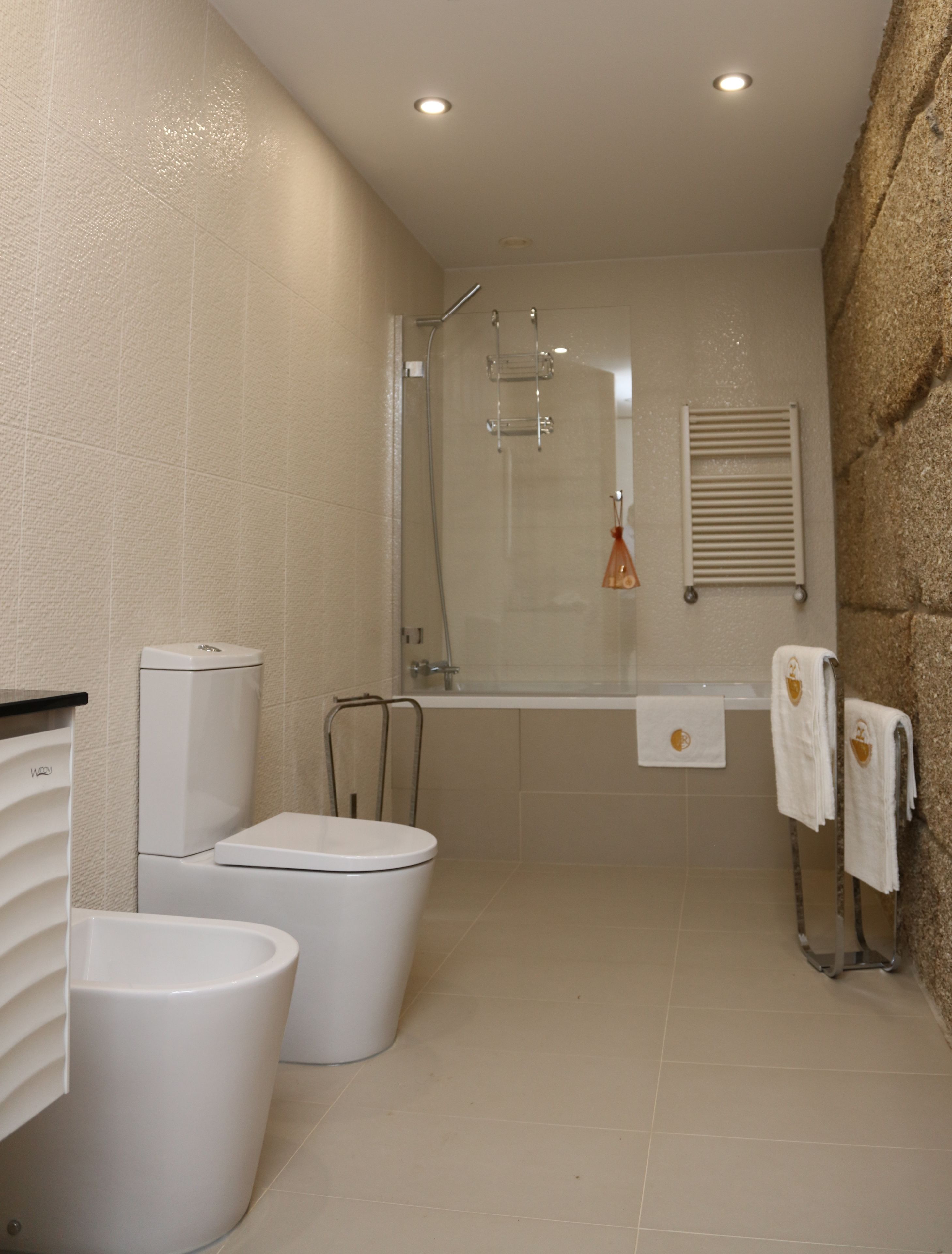 Une salle de bain moderne équipée de toilettes, d’un bidet et d’une douche séparée par des parois en verre.