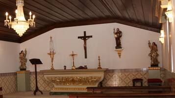 A church interior with a wooden ceiling, a chandelier, a cross, and statues.
