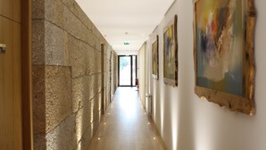 Un pasillo con paredes de piedra, puertas de madera y obras de arte en las paredes.