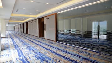 A long corridor with patterned carpet, glass partitions, and doors leading to rooms.