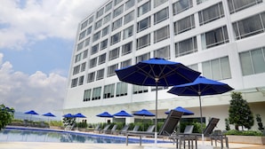 Ein Hotel mit Schwimmbad, blauen Sonnenschirmen und Liegestühlen.