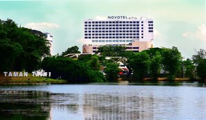 Un hotel Novotel con vistas a un lago y vegetación circundante.
