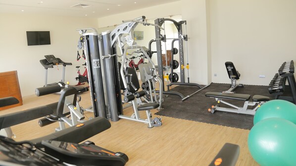 Un gimnasio con máquinas de cardio, equipo de levantamiento de pesas y una cinta de correr.