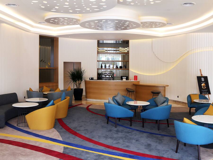 A modern lobby with seating areas, a bar, and a reception desk.