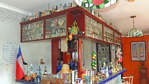 A bar area with a glass display case filled with bottles, a wooden counter with various items, and a flag on the left. - Panama Canal Inn (Panama City)
