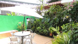 An outdoor patio with a round table and chairs, surrounded by lush greenery and a green wall. - Panama Canal Inn (Panama City)