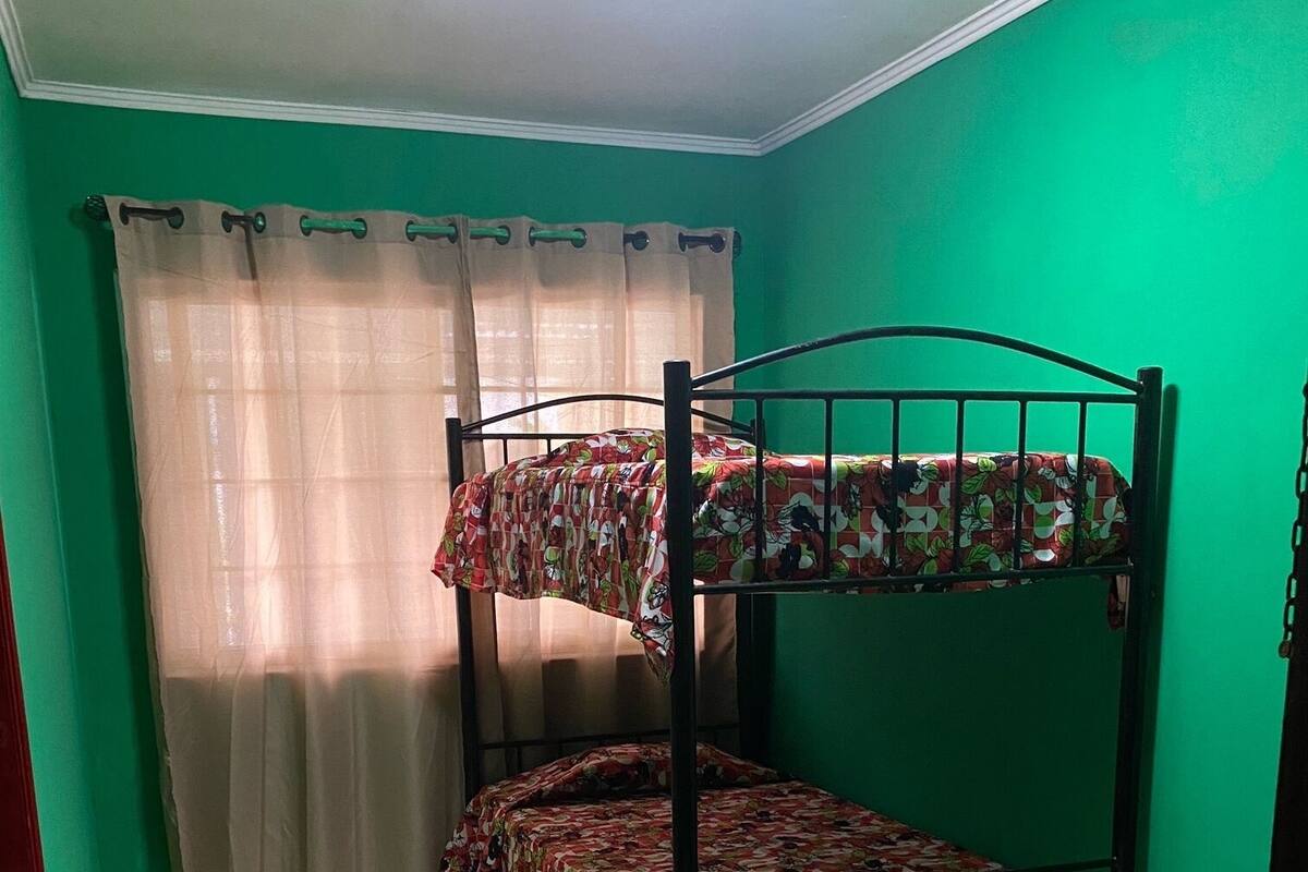 A bunk bed with floral bedding in a room with green walls and a tiled floor.