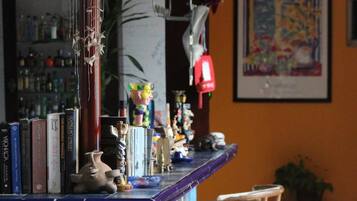 Una zona de bar con una estantería de libros, un jarrón decorativo y varios objetos pequeños.
