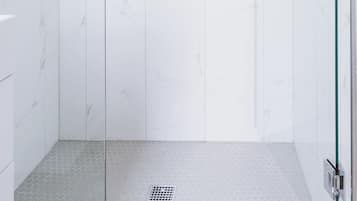 Una ducha moderna con puertas de vidrio, un panel de control y un estante con artículos de aseo.
