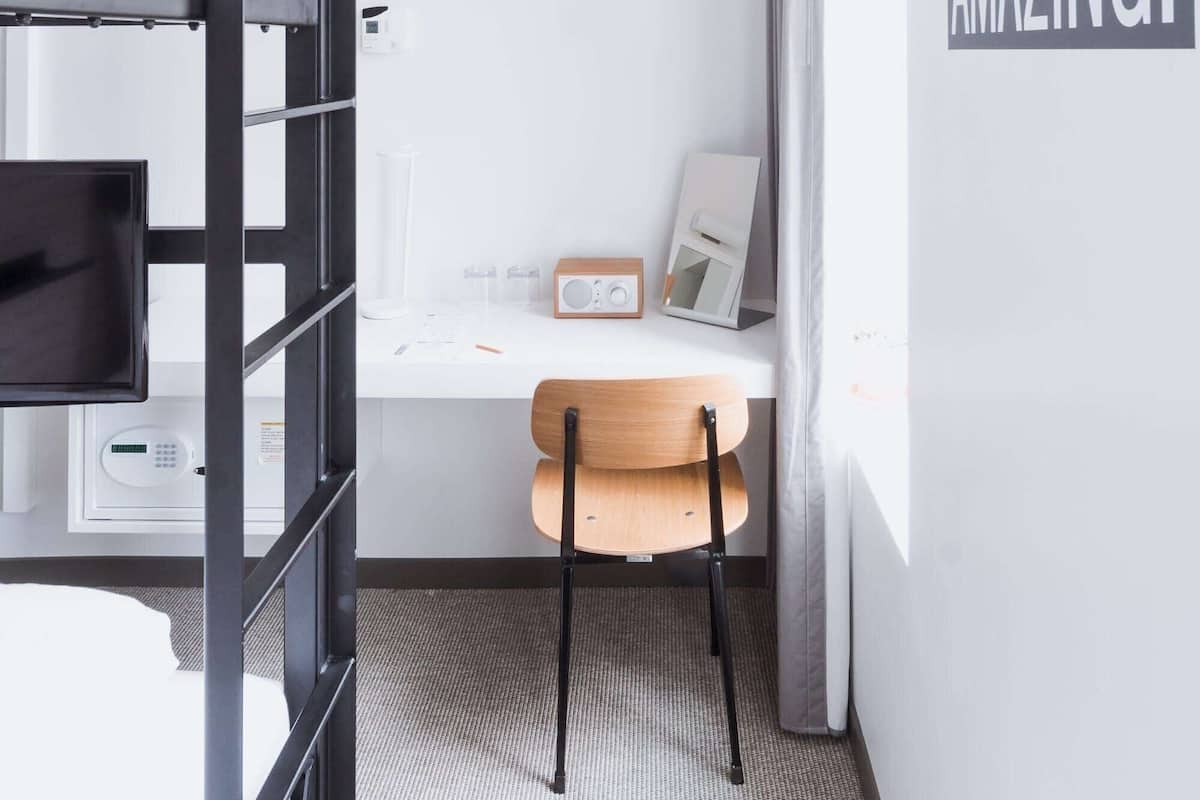 A modern, minimalistic room with a bunk bed, a desk, and a motivational wall decal.