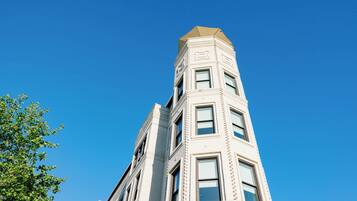 A tall, white building with a corner entrance and multiple windows.