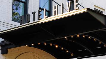Un hotel con un cartello ben visibile con la scritta "HOTEL HIVE" sopra l'ingresso.