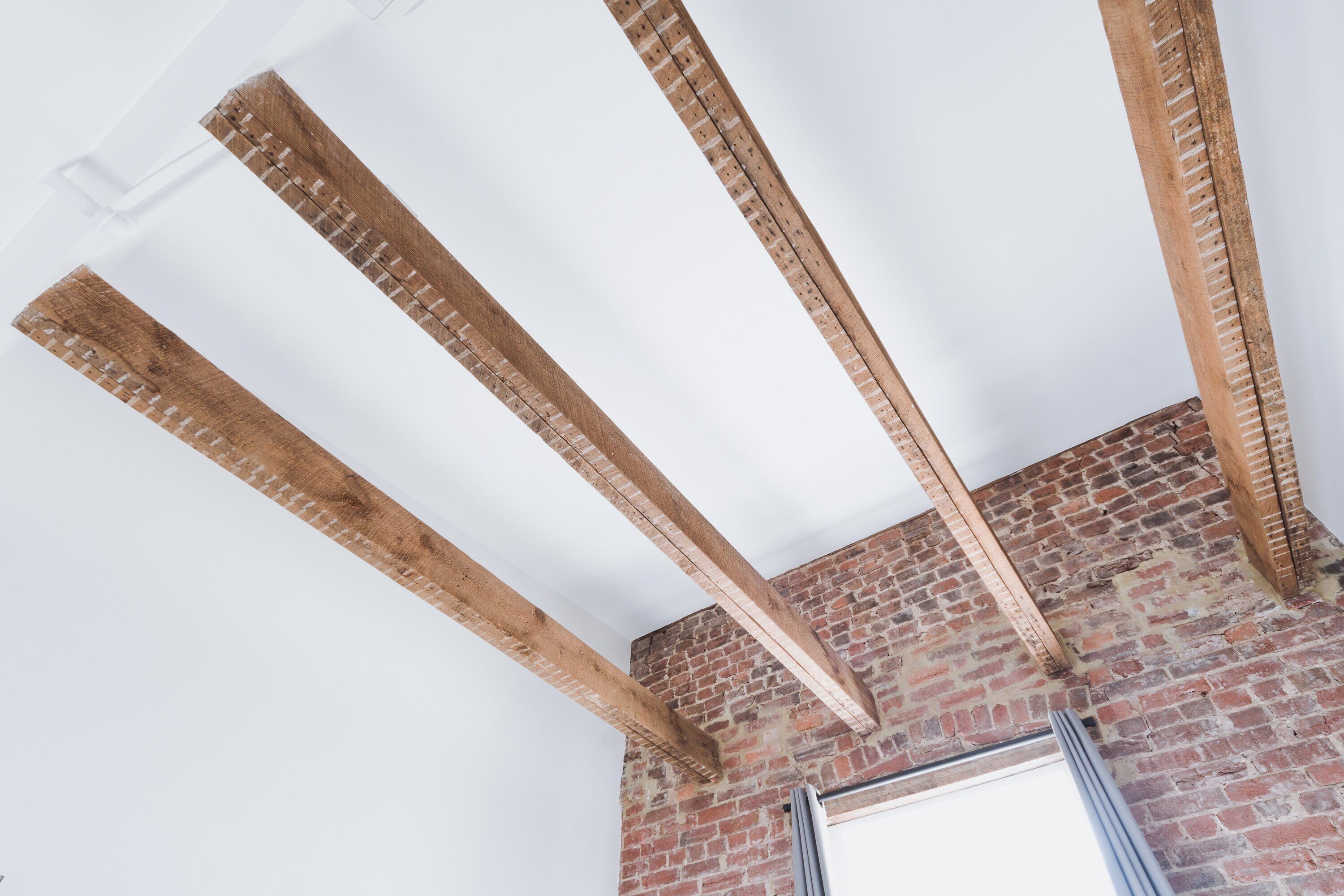 A room with exposed wooden beams and a brick wall.