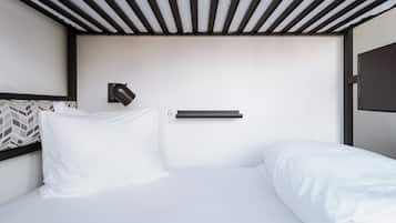 A modern hotel room with a bed, a wall-mounted lamp, and a power outlet.