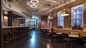 A modern bar area with stools, tables, and a counter. - Hotel Hive (Washington)