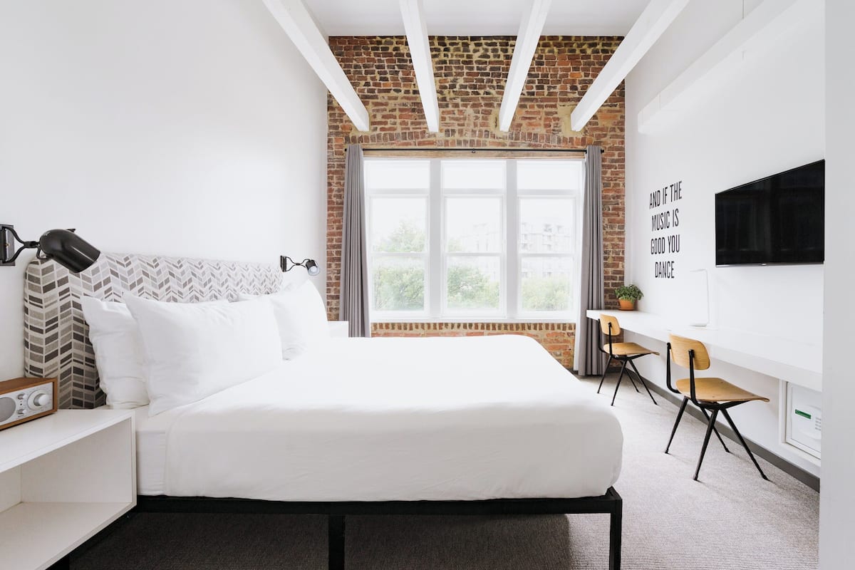 A modern hotel room with a large bed, a desk, and a TV.