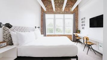 Una camera d'albergo moderna con un letto grande, una scrivania e una TV.