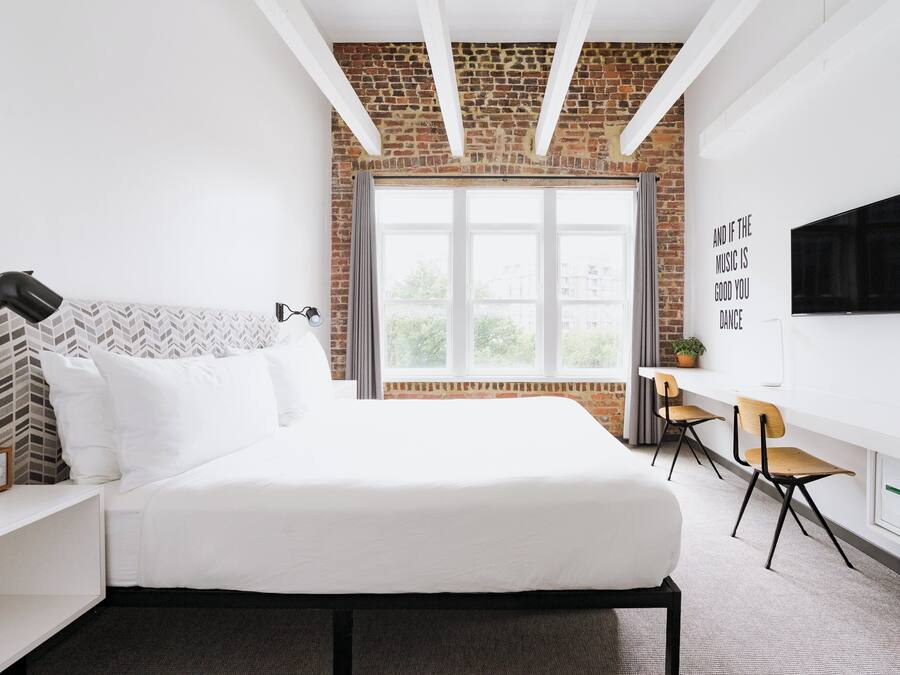 Ein modernes Hotelzimmer mit einem großen Bett, einem Schreibtisch und einem Fernseher.