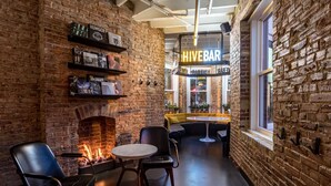 A cozy lounge area with a brick wall, a fireplace, and seating arrangements. - Hotel Hive (Washington)