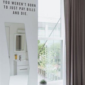 A modern bathroom with a large mirror, a sink, and a potted plant.