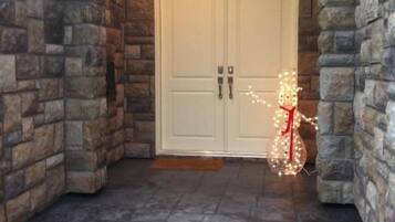 Une entrée aux murs de pierre, dotée d’une double porte et d’une décoration illuminée.