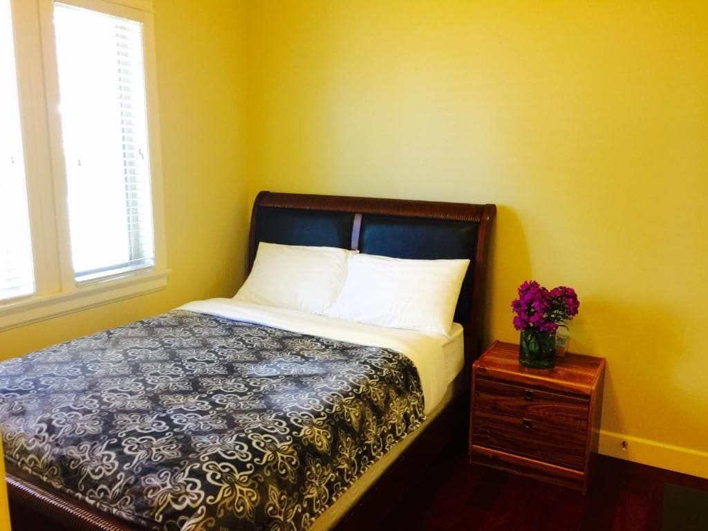 A bedroom with a bed, a nightstand, and a window.