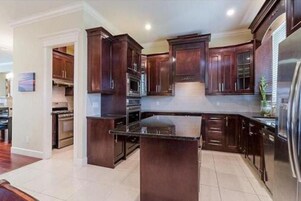 Una cocina moderna con armarios de madera oscura, una isla central y electrodomésticos de acero inoxidable.