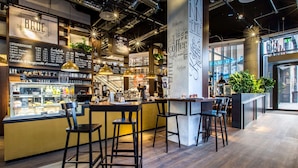 A modern coffee shop interior with a bar area, seating, and a menu board. - Radisson Blu Hotel, Mannheim (Mannheim)