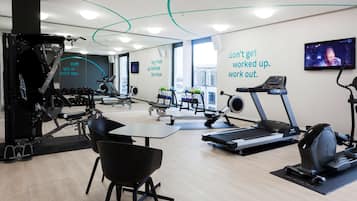 Un gimnasio moderno con máquinas de cardio, pesas y una frase motivadora en la pared.