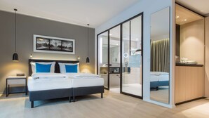 A modern bedroom with a bed, bedside tables, a large mirror, and a sliding door leading to a bathroom. - Radisson Blu Hotel, Mannheim (Mannheim)