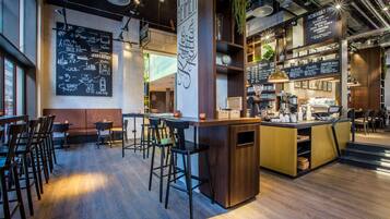 Un área de bar moderna con suelo de madera, taburetes y una barra con equipo para preparar café.