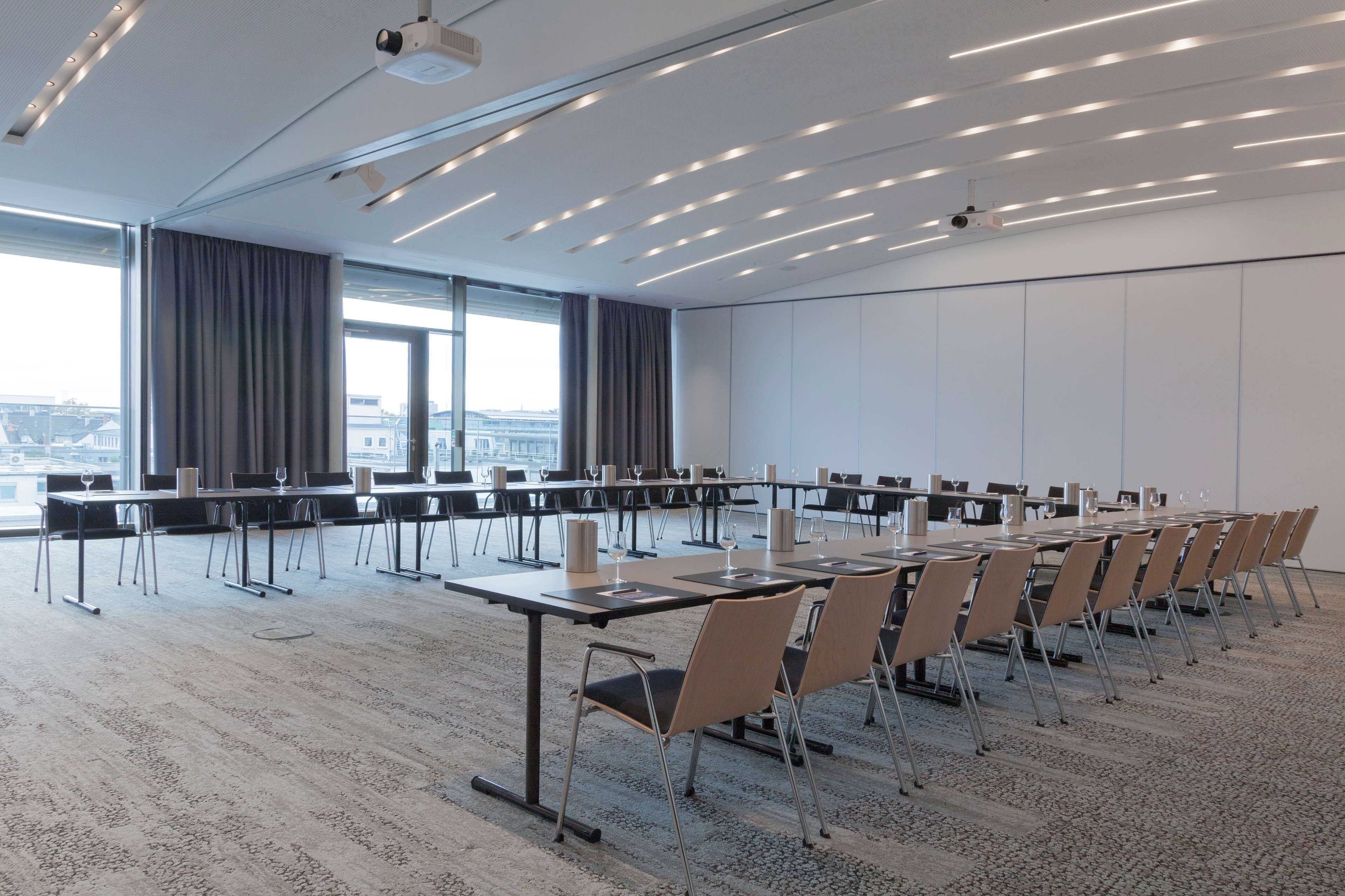 A conference room with long tables, chairs, and a projector.