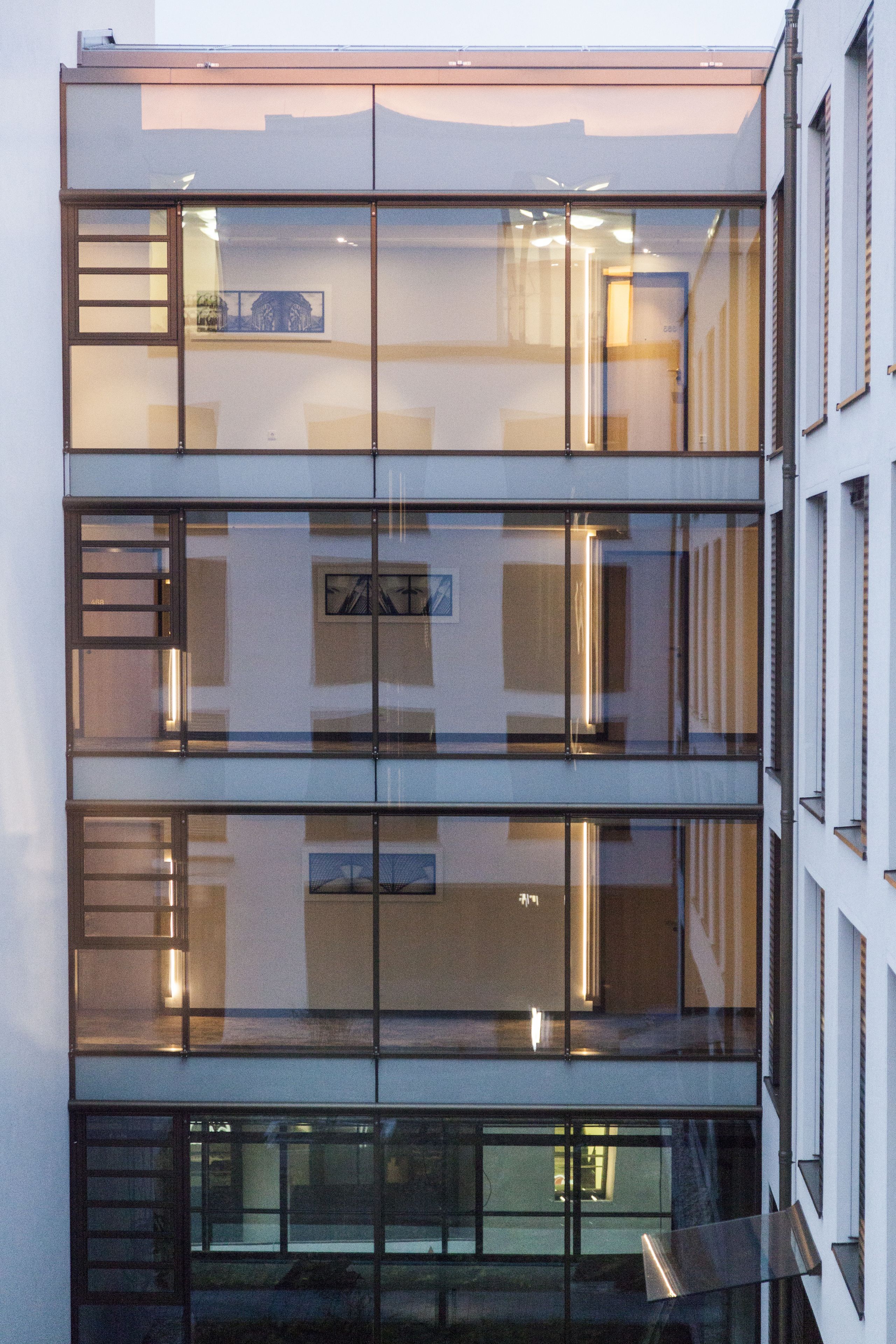 Ein mehrstöckiges Gebäude mit großen Glasfenstern und modernem architektonischen Design.