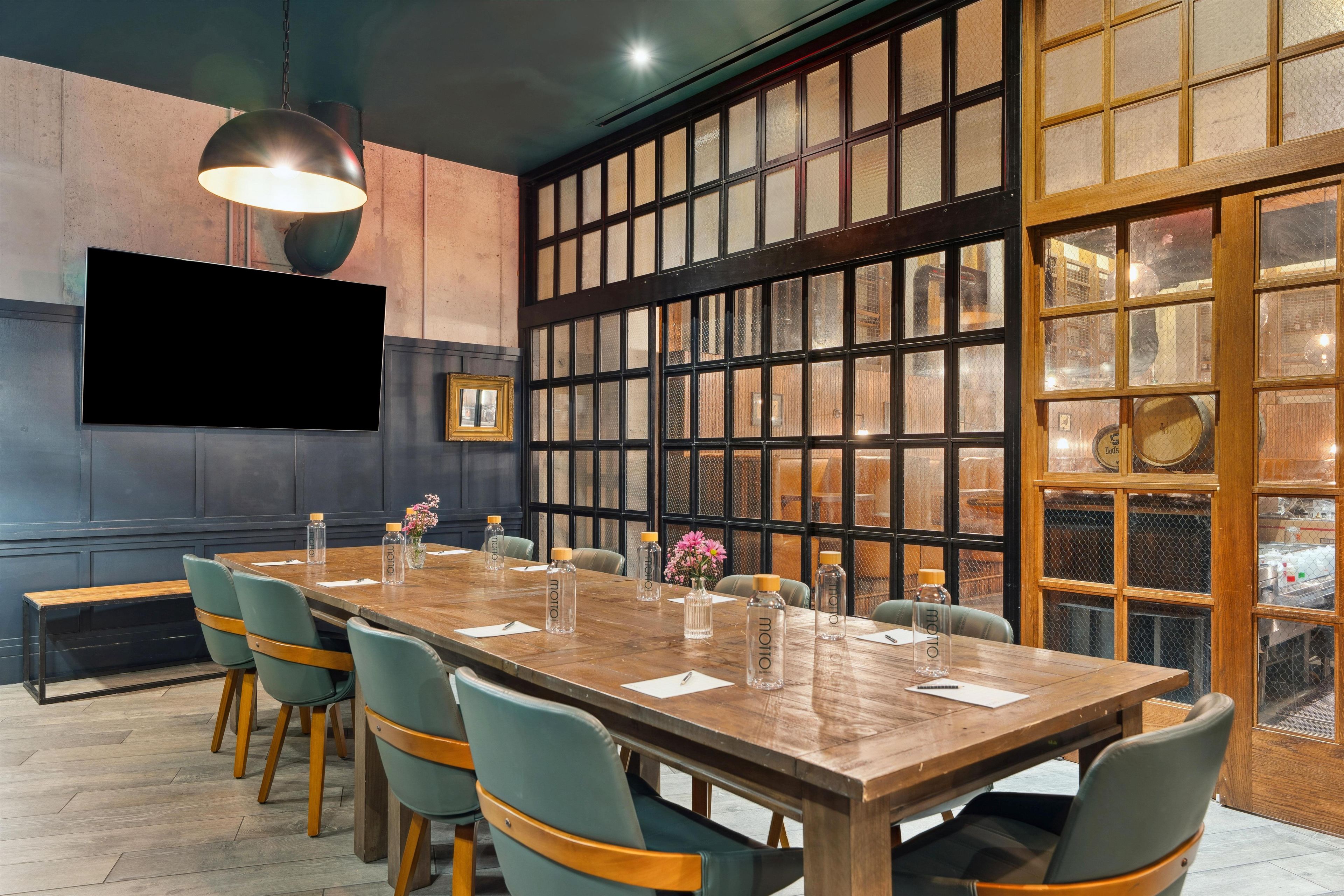 A conference room with a long table, chairs, a television, and a large window with a view.