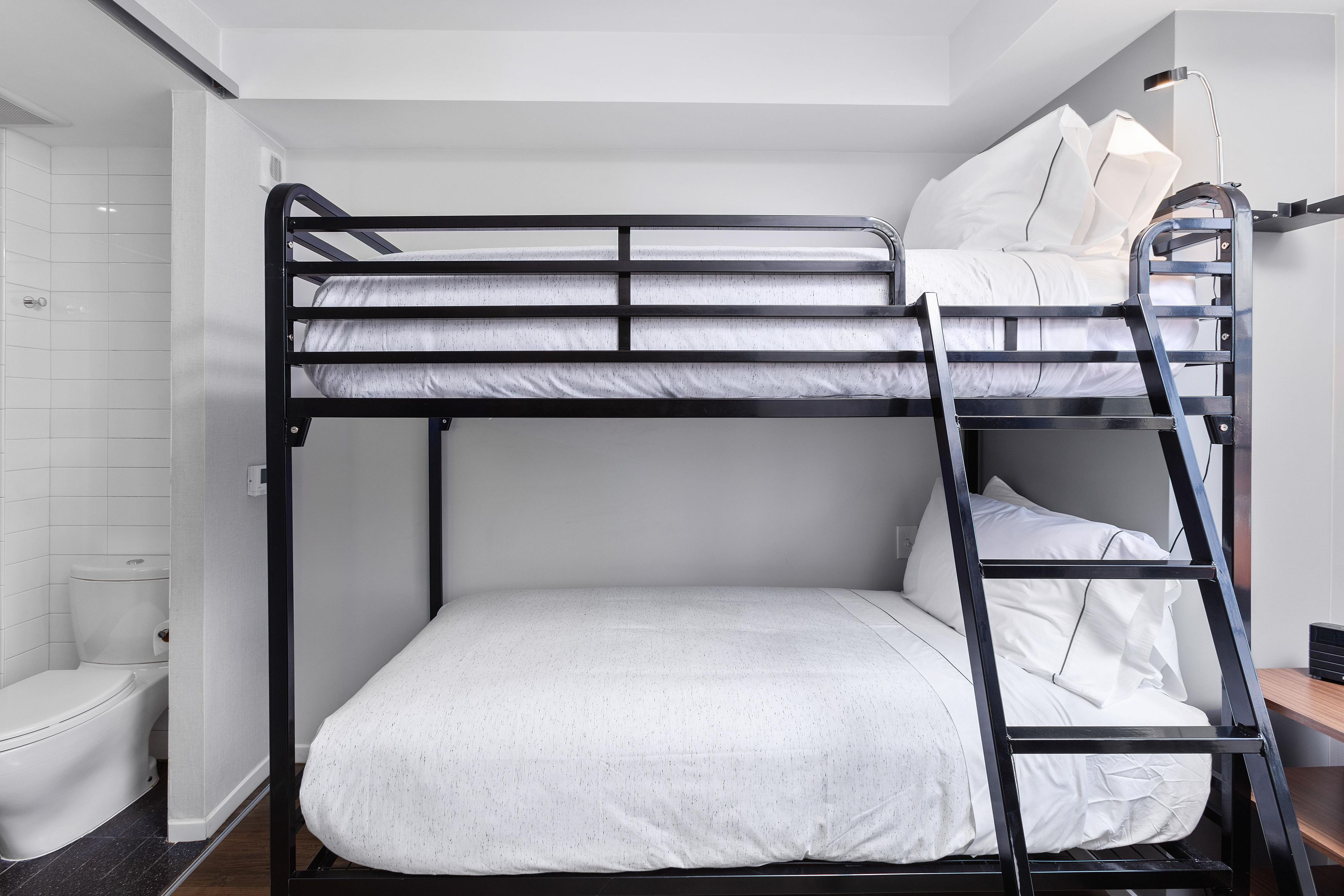 A bunk bed with a ladder, a toilet, and a shower area.