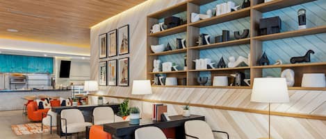 A modern interior with a dining area, bookshelves, and a kitchen in the background.