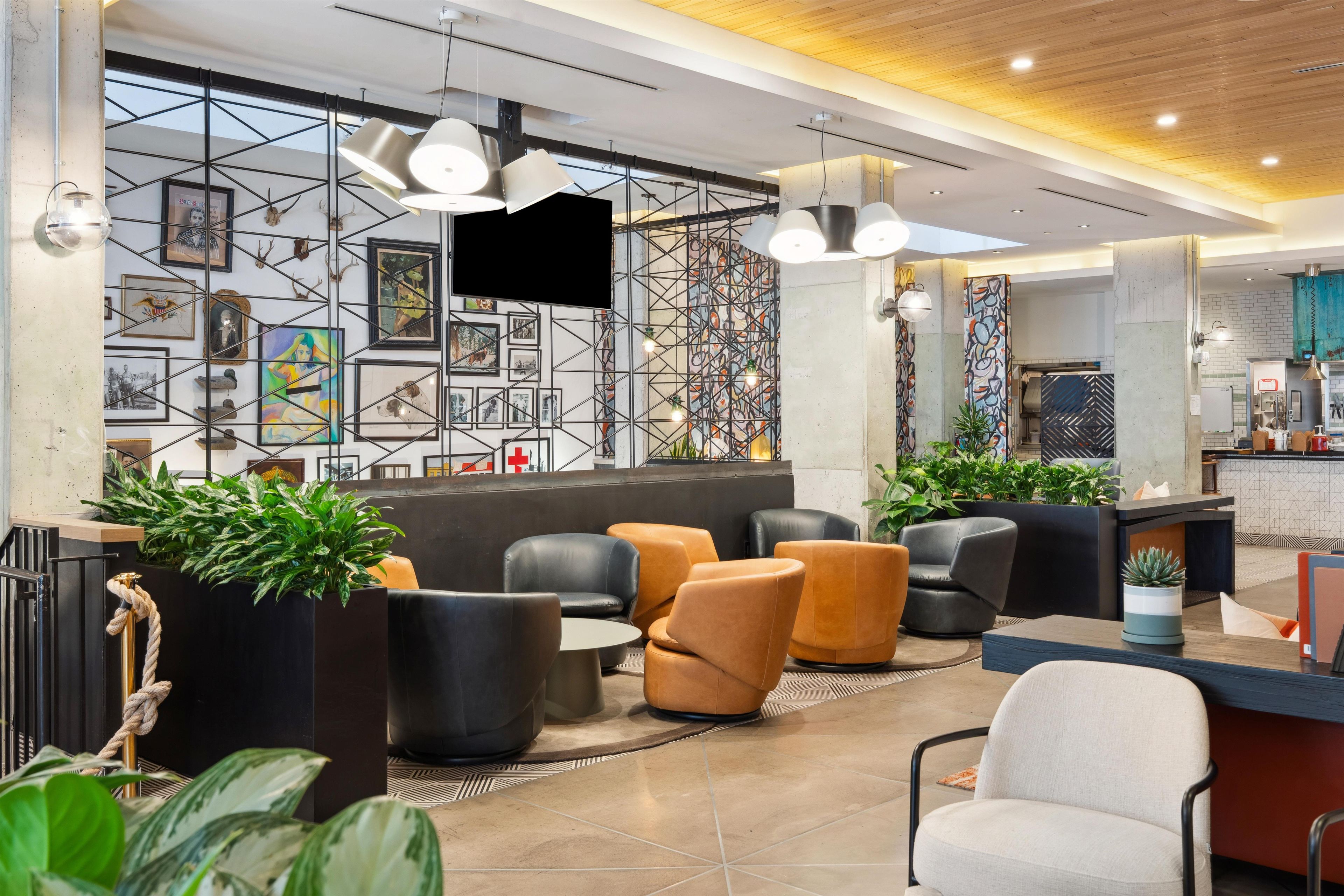 Un hall d’entrée moderne, doté d’espaces de détente, d’un comptoir d’accueil et d’un mur orné d’œuvres d’art encadrées.