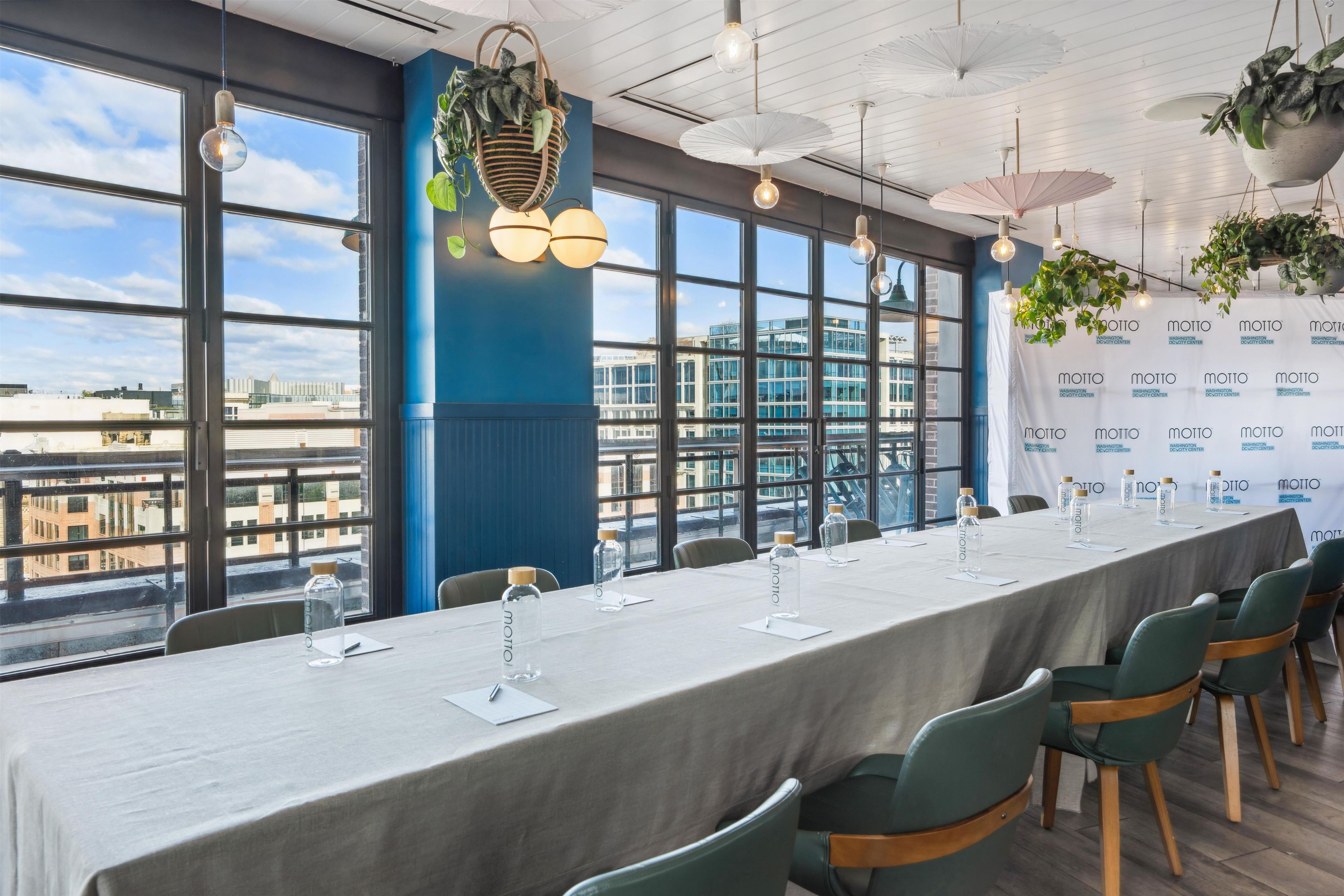 A conference room with a long table, chairs, and a backdrop with logos.